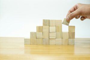 A person placing a block into a pile of wooden blocks