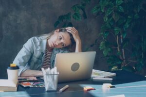 A woman appears stressed while working on laptop.