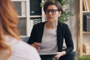 a woman sitting on a couch talking to another woman