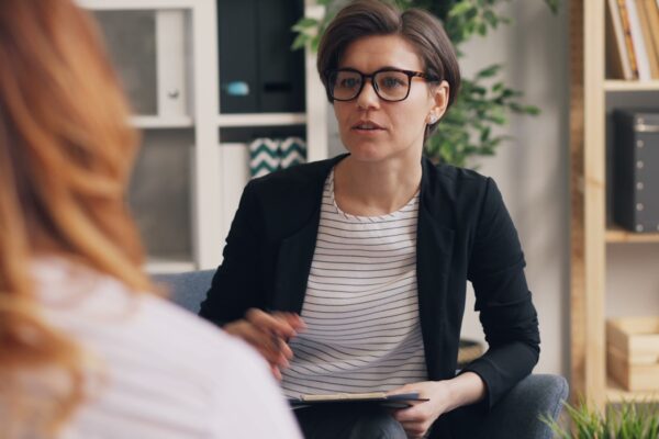 a woman sitting on a couch talking to another woman