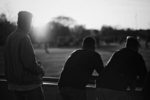 grayscale photography of three men standing near railings